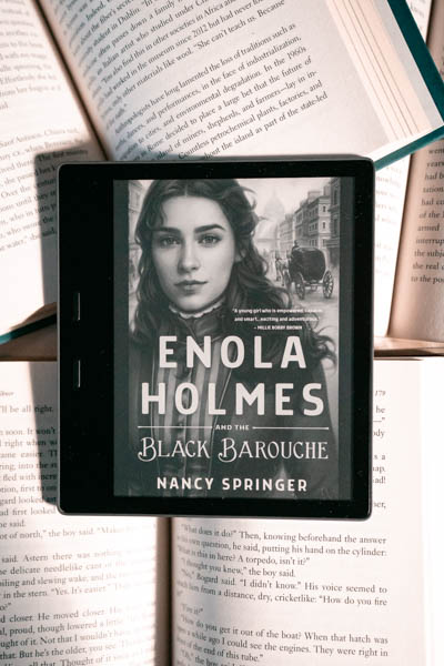 A closer picture of my Kindle Oasis opened to the cover art for Enola Holmes and the Black Barouche.