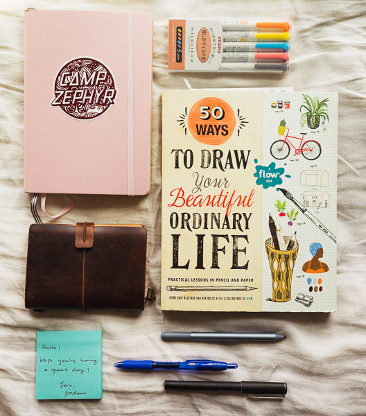 50 Ways to Draw Your Beautiful Life book, notebooks, and pens all lined up.