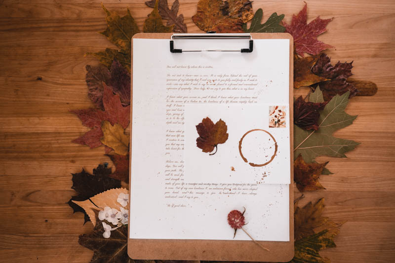 A warm picture of a letter I'm writing attached to my clipboard holding all the leaves I've collected this fall.